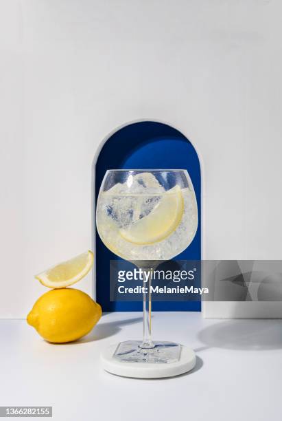 gin tonic cocktail aperitif with lemon zest and ice on minimal background - gin and tonic stock pictures, royalty-free photos & images