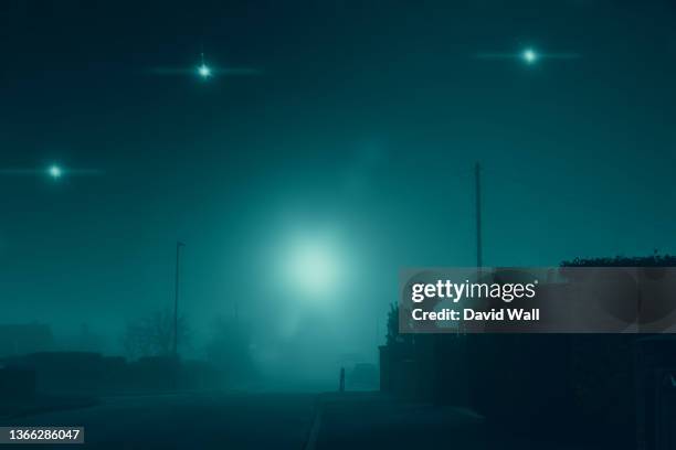 glowing ufo lights in the sky. in a quiet empty road in a suburban town. on a quiet, atmospheric foggy winters day. uk - ufo fotografías e imágenes de stock