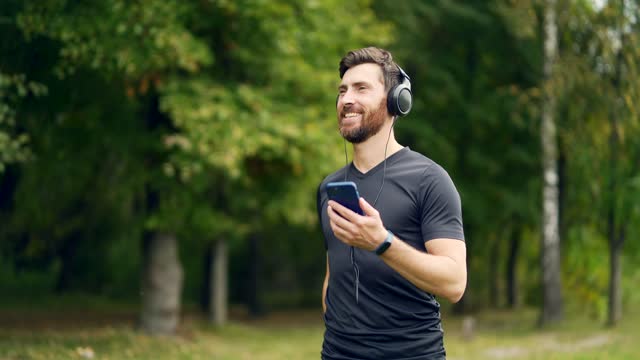 young cheerful active guy sporty walking with headphones mobile phone enjoying listening to music