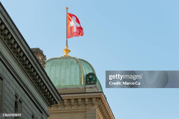 die schweizer flagge auf dem eidgenössischen parlamentsgebäude in bern - bundestag stock-fotos und bilder