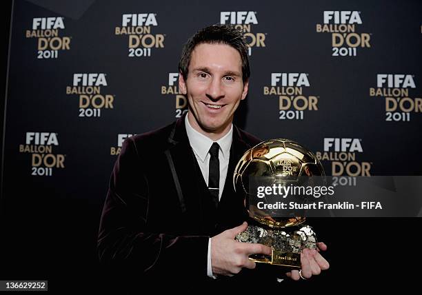 Lionel Messi of Argentina poses with the trophy after winning his third consecutive FIFA Ballon d'Or title at the FIFA Ballon d'Or Gala 2011 at the...