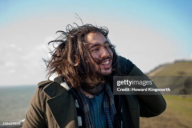 portrait of young man on windswept clifftop - cheveux au vent photos et images de collection