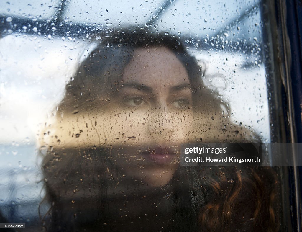 Portrait of female through rain covered window