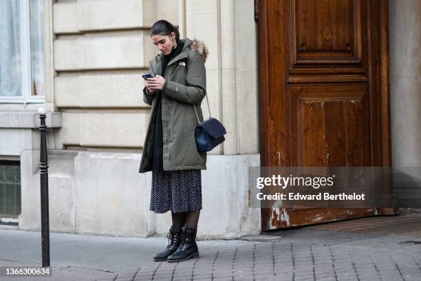 Guest wears a black with white polka dots long dress, a khaki long puffer jacket with brown fur hoodie, black tights, black shiny leather laces ankle...