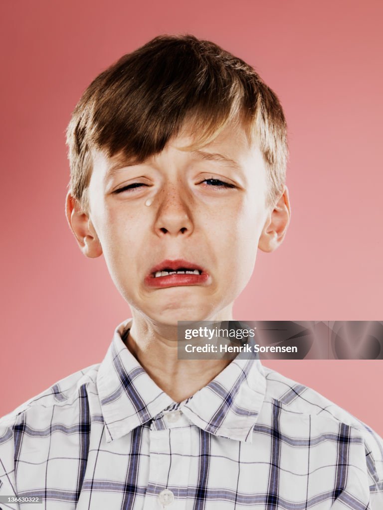 Portrait of young boy crying with funny face
