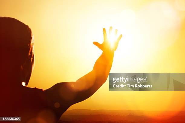 young woman reaching for the sun. - heat temperature stock-fotos und bilder