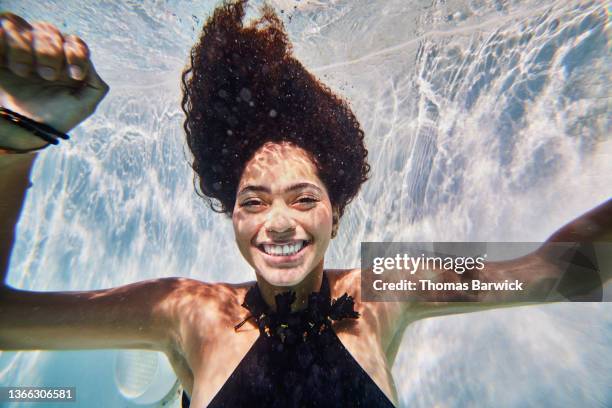 medium shot of smiling woman underwater in pool while on vacation - unterwasseraufnahme stock-fotos und bilder