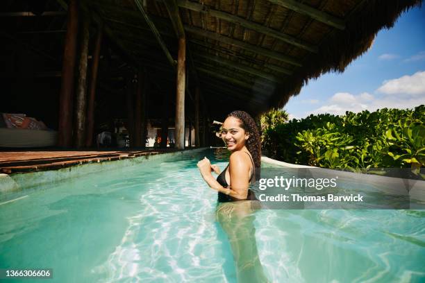 wide shot of smiling woman relaxing in pool at luxury tropical  villa - portrait pool stock pictures, royalty-free photos & images