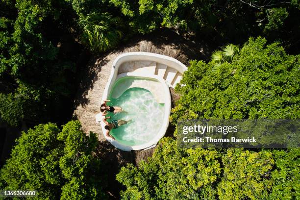 wide shot overhead aerial view of couple relaxing in rooftop pool at eco jungle resort - rooftop pool stock-fotos und bilder