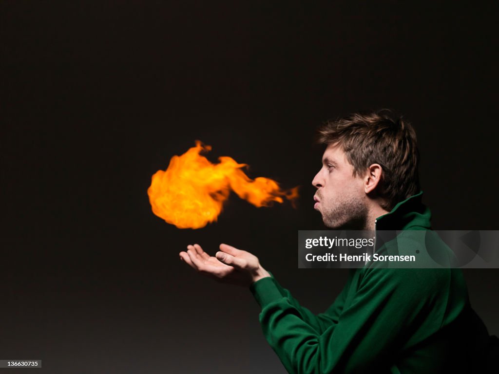 Young man blowing fireball