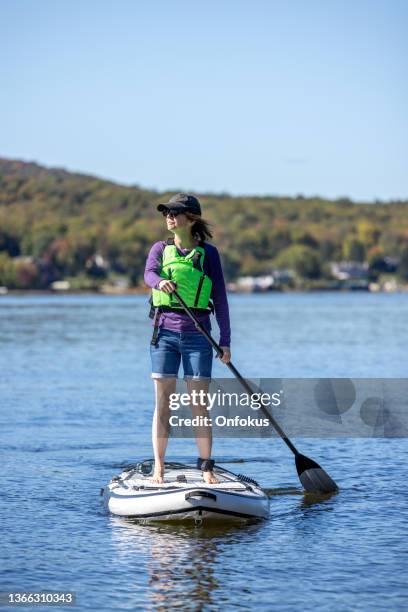 woman paddleboarding on the lake in autumn, quebec, canada - paddle board stock pictures, royalty-free photos & images