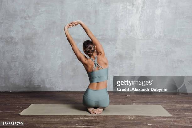 yogi woman practices yoga stretching sitting on mat in studio gym. sport and health lifestyle concept - stretching fotografías e imágenes de stock