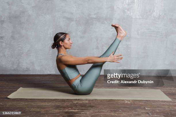 a yogi woman practicing yoga on a mat does an exercise on the abdominal muscles. sport and health concept - acrobatic yoga stock-fotos und bilder