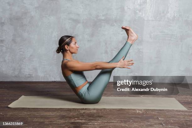 a yogi woman practicing yoga on a mat does an exercise on the abdominal muscles. sport and health concept - practicing fotografías e imágenes de stock