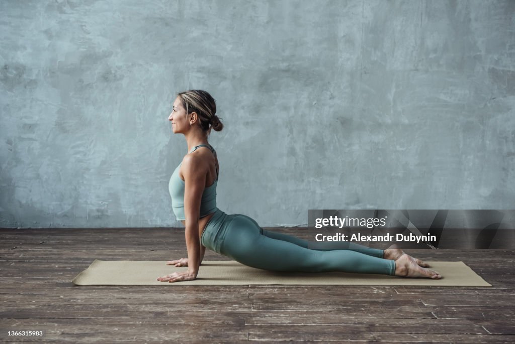 A woman practices yoga in the gym on a mat doing a stretching cobra pose. Sport and healthy lifestyle concept.