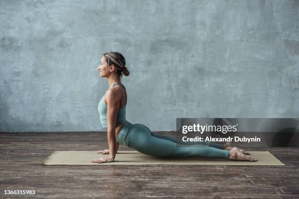 a woman practices yoga in the gym on a mat doing a stretching cobra pose. sport and healthy lifestyle concept. - kobra bildbanksfoton och bilder