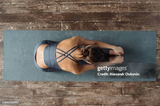 yogi woman, top view, practicing yoga on a mat on the floor, doing stretching in a relaxed pose. - yogi fotografías e imágenes de stock