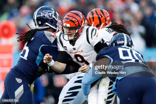 Quarterback Joe Burrow of the Cincinnati Bengals is hit by the Tennessee Titans defense after throwing a second quarter pass in the AFC Divisional...