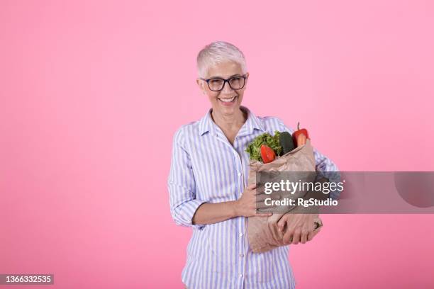 studio shot of a mature woman with a bag of groceries - food studio shot stock pictures, royalty-free photos & images