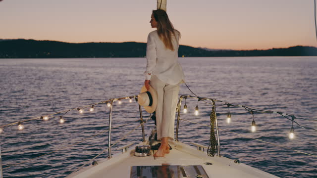 SLO MO Young woman enjoys the view from a deck of a sailboat at sunset