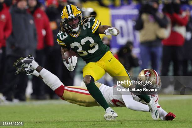 Running back Aaron Jones of the Green Bay Packers carries the ball as he avoids a tackle by defensive back Dontae Johnson of the San Francisco 49ers...