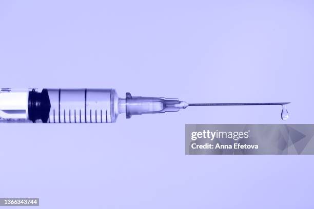 disposable sterile syringe with drop of fluid medication on thin needle on violet background. macro photography with copy space. demonstrating very peri - color of 2022 year - injecting ストックフォトと画像