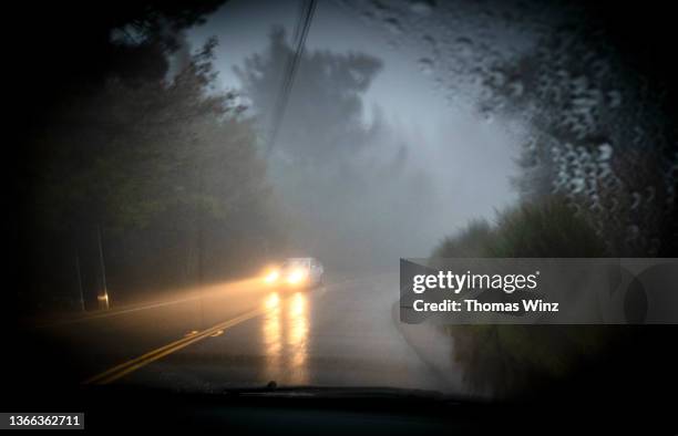 approaching car in the rain at dusk - dark country road stock pictures, royalty-free photos & images