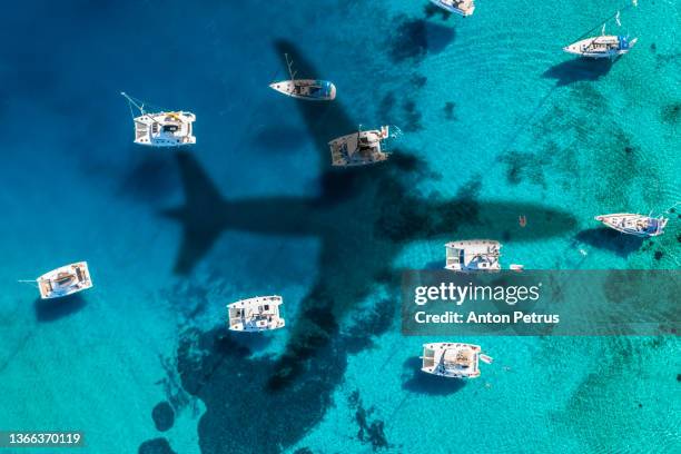 airplane shadow over the yachts in turquoise water near the island moni eginas, greece.  traveling in greece - être ancré photos et images de collection