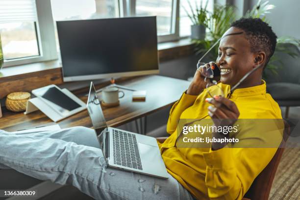 african american lady with laptop, sitting while talking over smartphone - teleworking hipster stock pictures, royalty-free photos & images