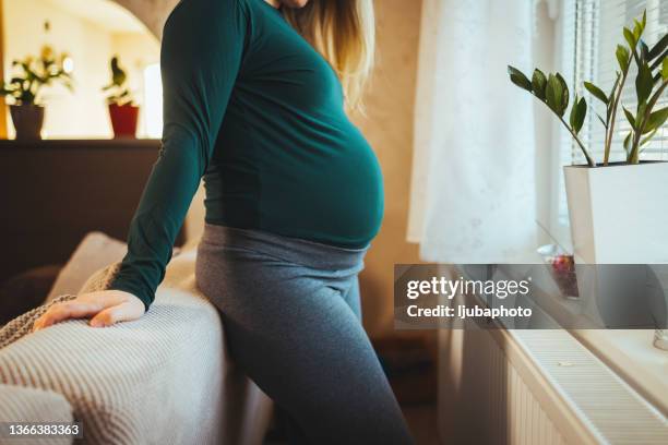 young happy pregnant woman standing by the window - maternity wear 個照片及圖片檔
