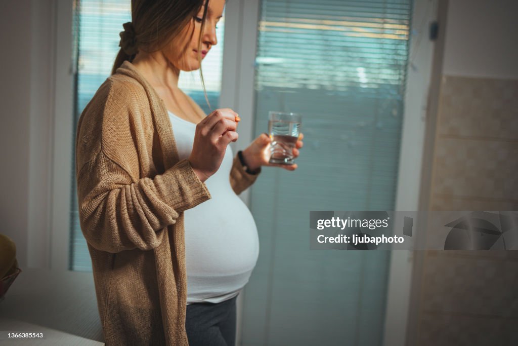 Young pregnant woman taking medicine