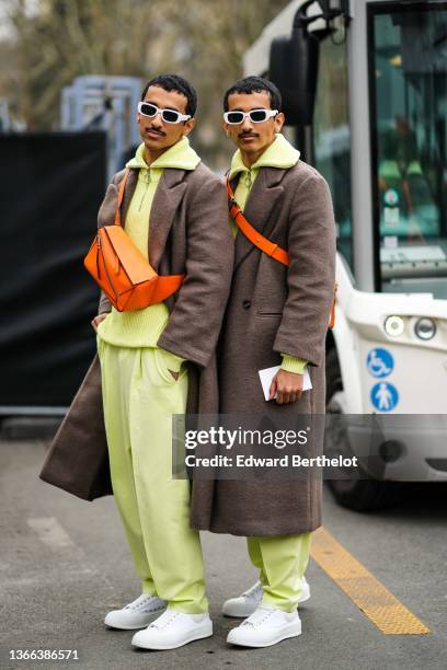 Twins Humaid Nadban and Mohammed Nadban are seen wearing white sunglasses, a yellow zipper high neck wool pullover, a brown fluffy long coat, an...