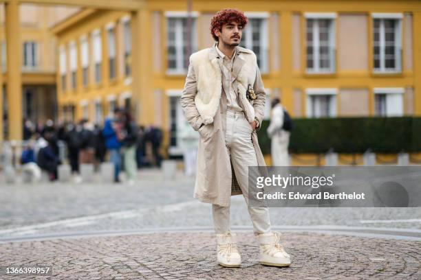 Guest wears a gold chain pendant necklace, a beige linen shirt, a beige jacket, a white fluffy sleeveless jacket, a brown shiny leather and pale...