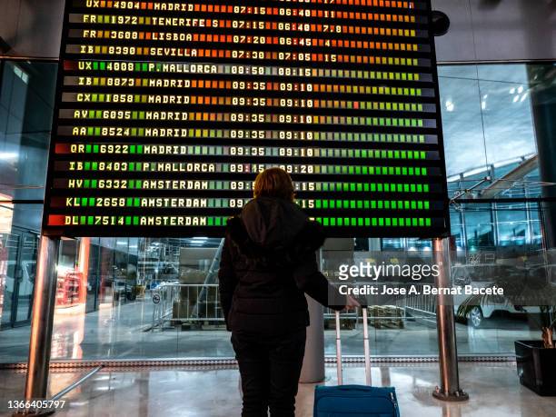 traveler adult woman looking at flight information at the airport. - arrival time stock pictures, royalty-free photos & images