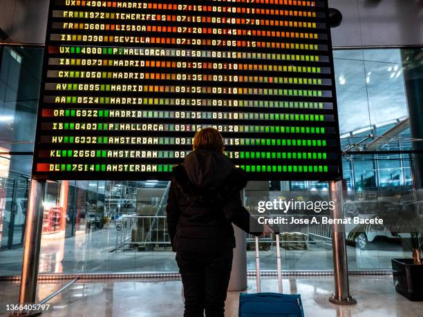 traveler adult woman looking at flight information at the airport. - voando - fotografias e filmes do acervo