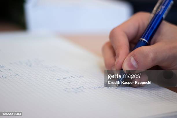 close up of solving mathematical equation on paper and writing them down with a pen - a grade stock pictures, royalty-free photos & images