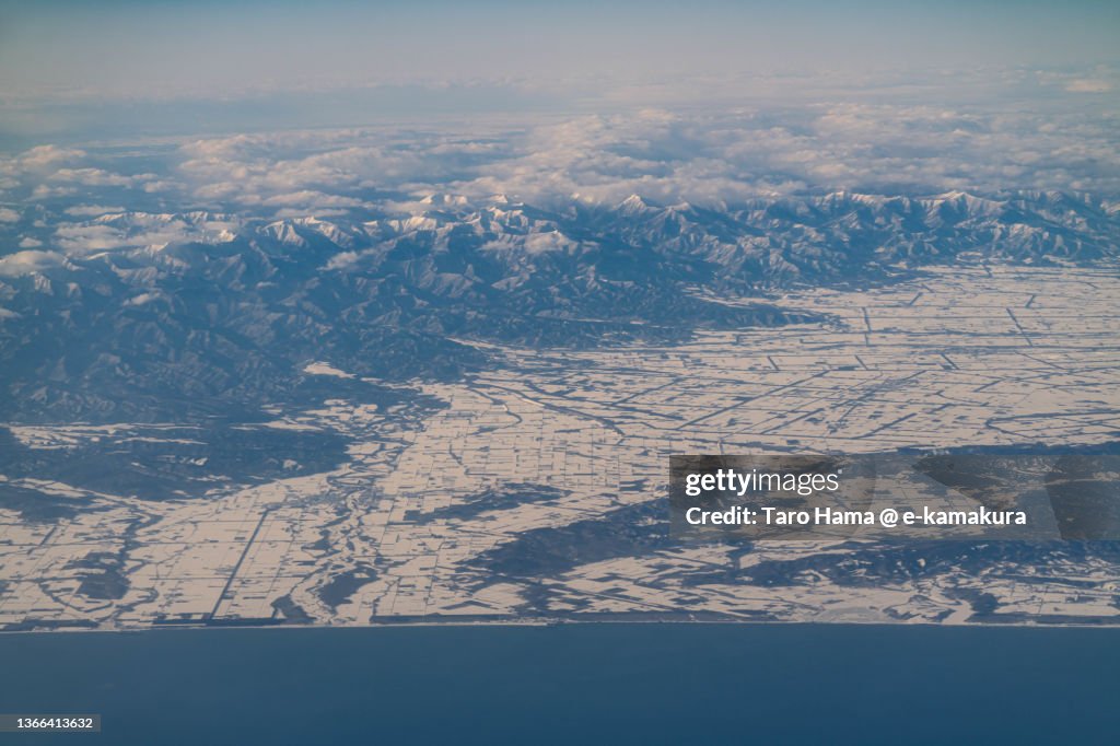Snowcapped Hidaka Mountains and Taiki town and Sarabetsu village in Hokkaido of Japan aerial view from airplane