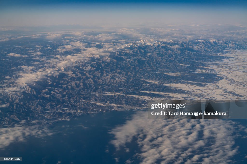Snowcapped Hidaka Mountains and Hiroo town in Hokkaido of Japan aerial view from airplane