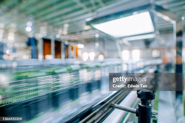 bewegung verschwommene schnell bewegende wasserflaschen an der mineralwasserfabrikproduktionslinie an der ziellinie in einer reihe bewegende warteschlange für die etikettierung der verpackung - bottle factory stock-fotos und bilder