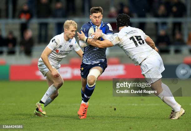 Tom Roebuck of Sale Sharks is tackled by Dan Evans and Matt Protheroe during the Heineken Champions Cup match between Sale Sharks and Ospreys at AJ...