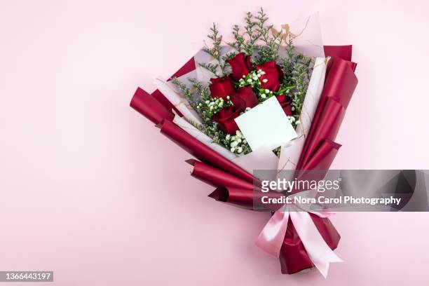 blank card on red roses bouquet on pink background - flower bouquet stockfoto's en -beelden