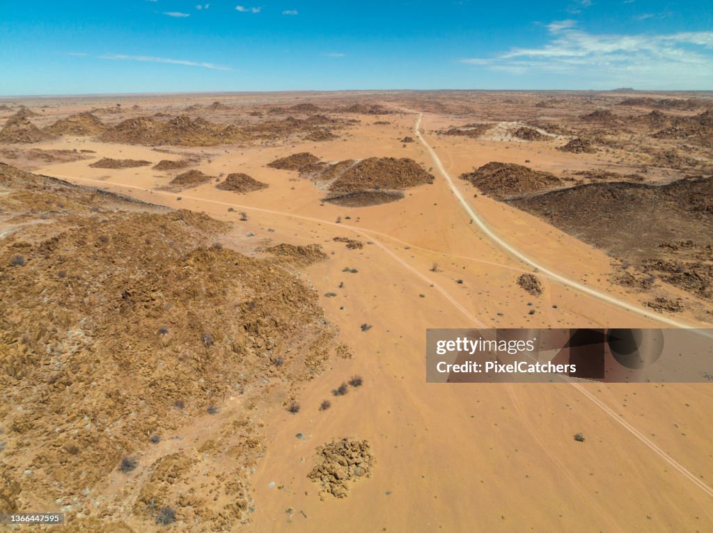 Dirt roads through rocky hills and sand to horizon
