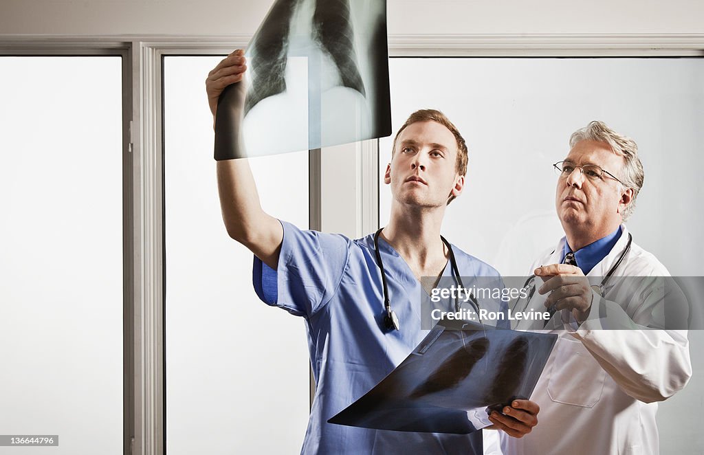 Mature doctor and resident examining chest x-rays