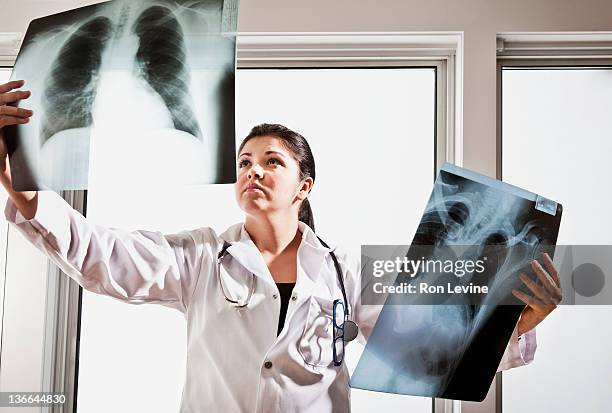 female hispanic doctor examines chest x-rays - röntgen stockfoto's en -beelden