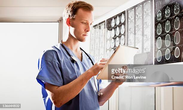 doctor uses a digital tablet at a radiology clinic - back lit doctor stock pictures, royalty-free photos & images