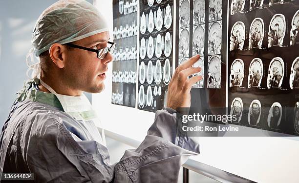 doctor in surgical wear examines mri scan - human head photos et images de collection