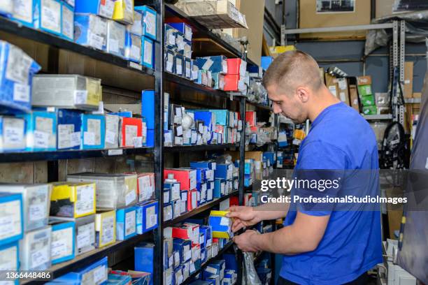 photo of an experienced car mechanic who is looking for car part in large store. - del på fordon bildbanksfoton och bilder