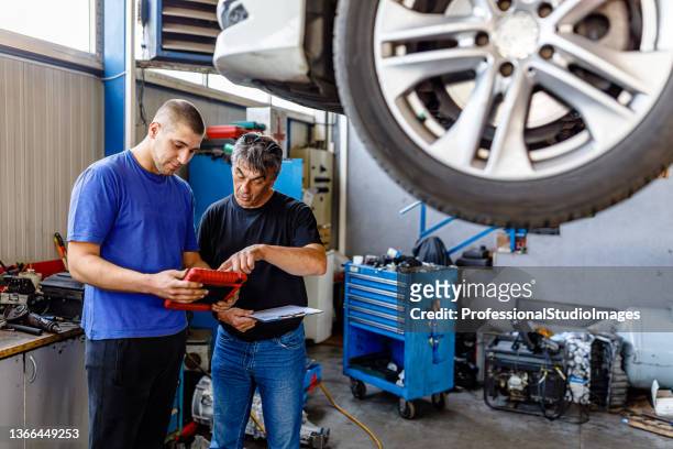 a man with car problems is analyzing problems with a car mechanic. - garage home car repair stock pictures, royalty-free photos & images