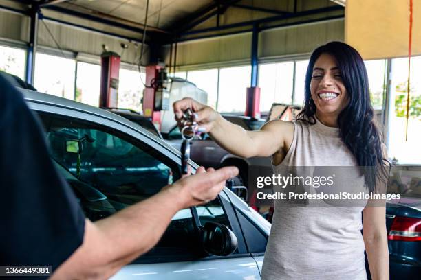 junge geschäftsfrau gibt einem mechaniker in der servicewerkstatt die schlüssel eines autos. - happy client by broken car stock-fotos und bilder