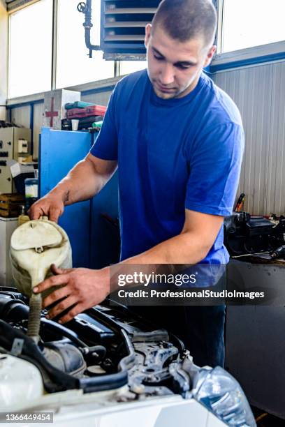 photo of an experienced car mechanic who is changing oil in motor of a car. - engine failure stock pictures, royalty-free photos & images